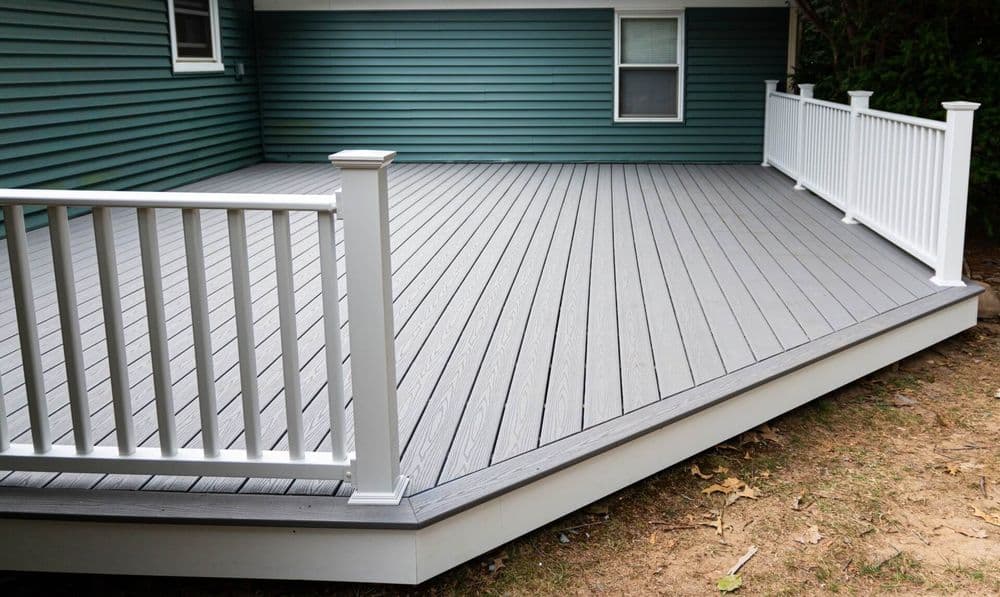 Composite deck with white railing and green siding, showcasing a spacious outdoor living area.